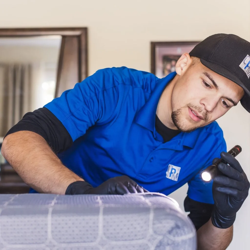 Bed bug exterminator checking for bed bugs on mattress with flash flight